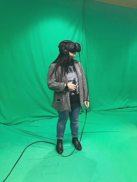 A person wearing a virtual reality headset in front of a greenscreen.