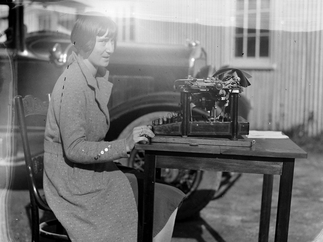 Black and white photograph of a woman seated at desk with a typewriter].jpeg