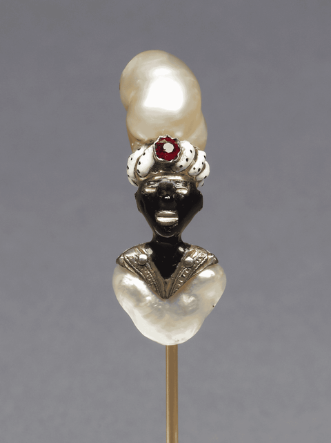 The head of the gold pin is in the form of an African with an enameled face. Both his turban and che