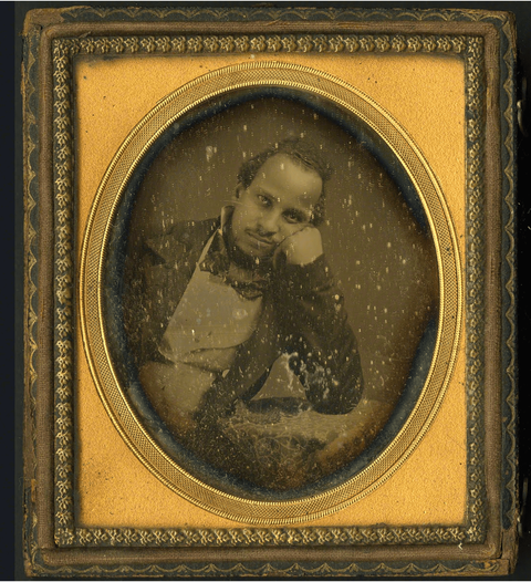 Framed daguerreotype portrait of Alexander Thomas leaning against a table while seated. Thomas is we