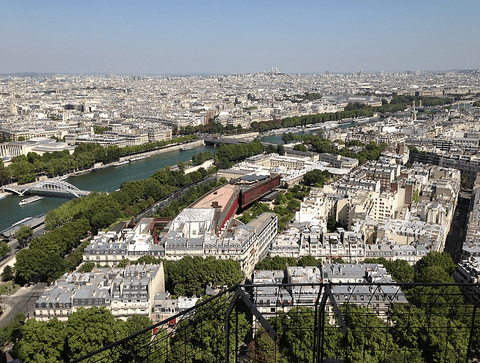 A photo of a view over Paris from the Eiffel tower. The Seine River is at the top left of the image.