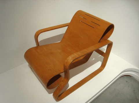 Lounge chair with a single sheet of bent plywood that forms the back and seat, held in place in a th